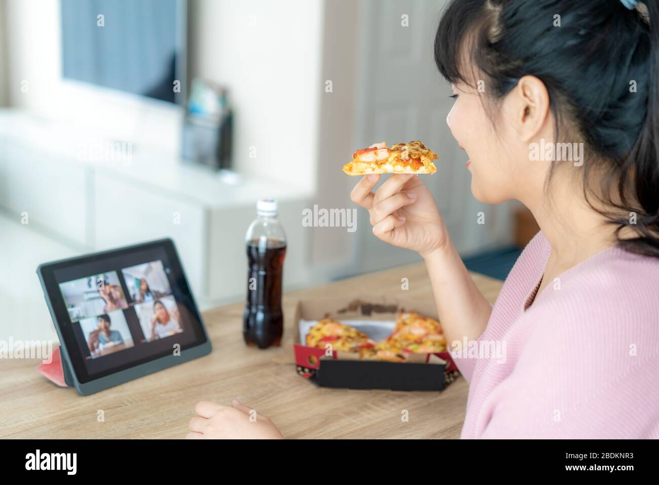 Une femme asiatique a une fête virtuelle de l'happy hour et manger de la nourriture en ligne avec son ami en visioconférence avec tablette numérique pour une rencontre en ligne Banque D'Images