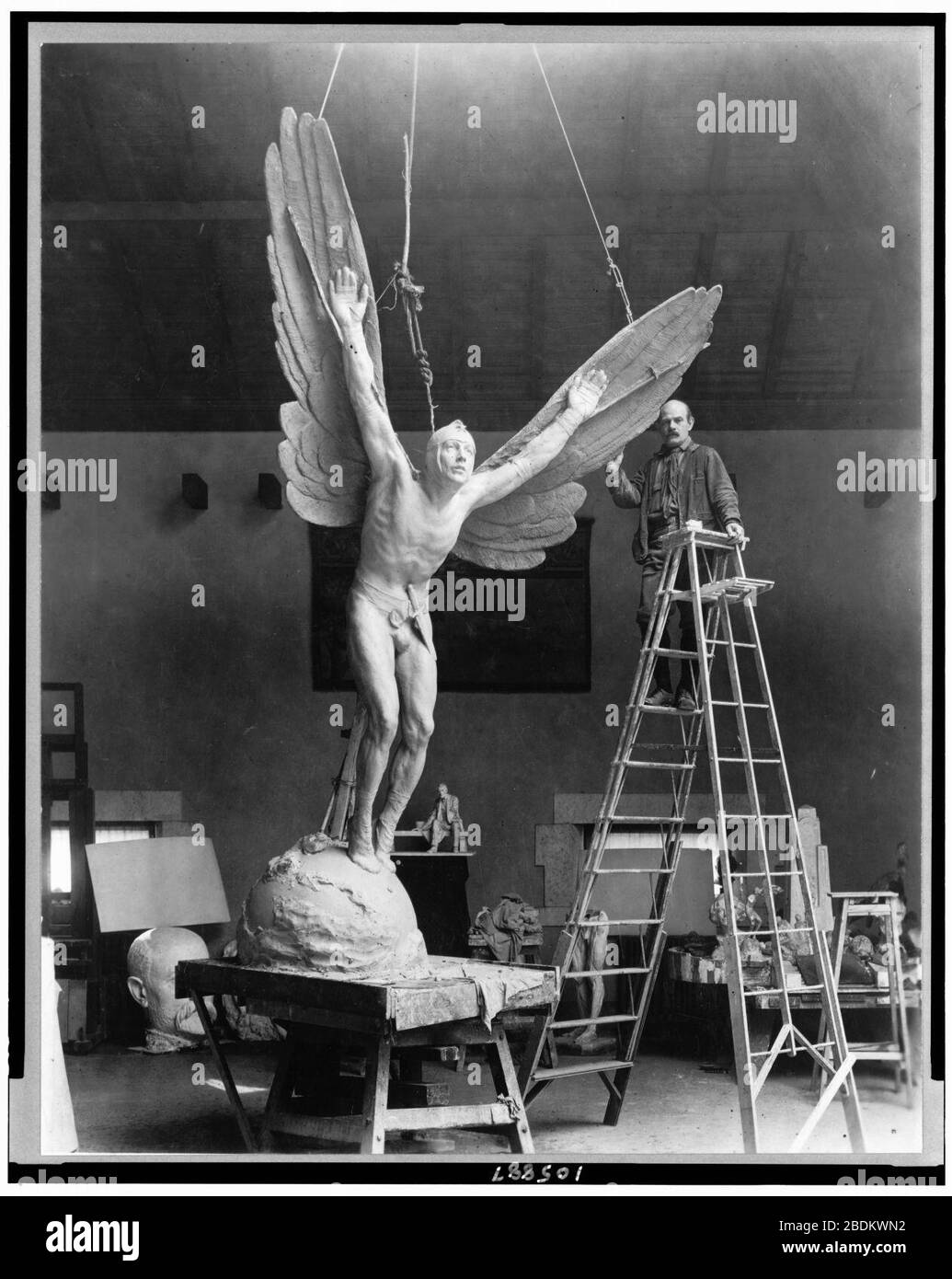 Gutzon Borglum, sculpteur, portrait sur toute la longueur, debout sur l'échelle, aux côtés de sa sculpture, Statue d'aviateur, face légèrement à gauche Banque D'Images