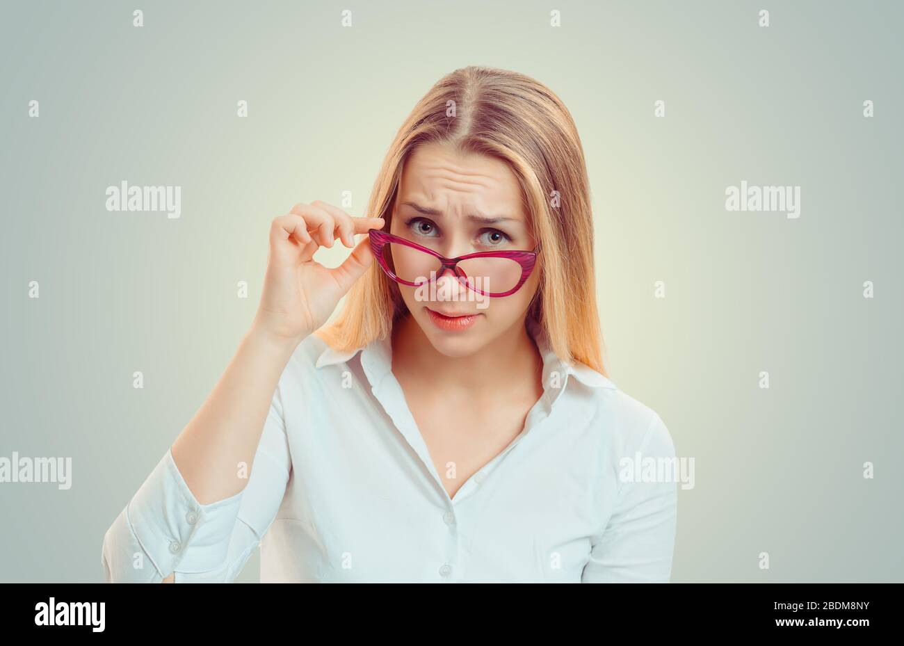 Headshot sérieuse femme sorceuse en colère tenant des lunettes de soleil vers le bas sceptique regardant vous isolé vert jaune mur fond, chemise blanche. Humain Banque D'Images