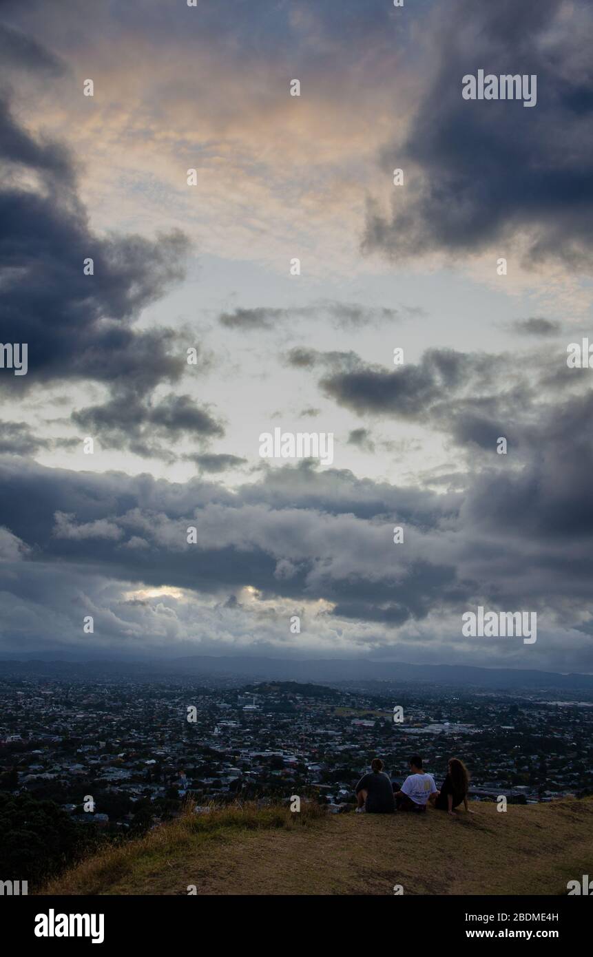 AUCKLAND, NOUVELLE-ZÉLANDE - 4 avril 2020: Les amis regardant le coucher de soleil du mont eden sur une soirée nuageux à auckland Banque D'Images