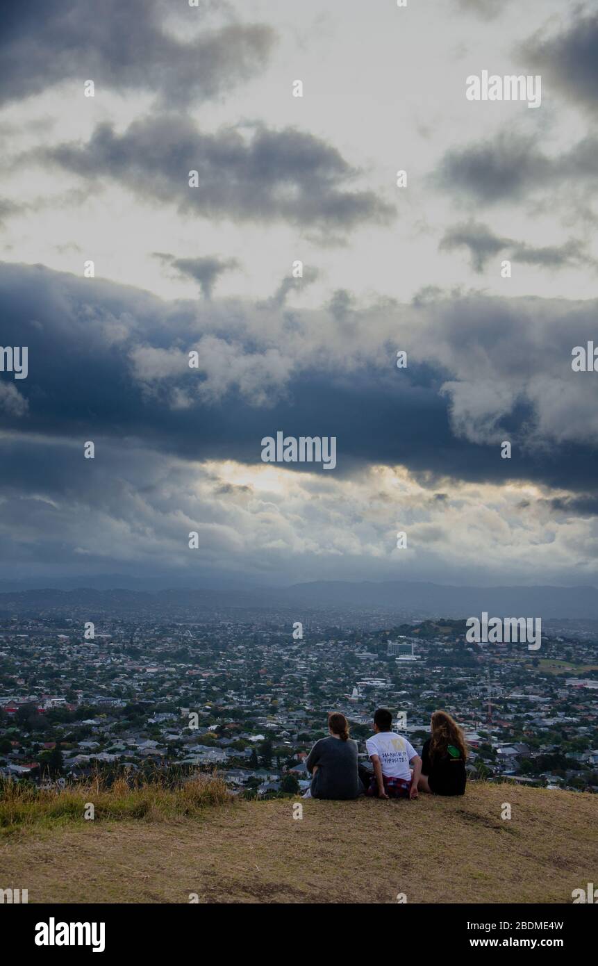 AUCKLAND, NOUVELLE-ZÉLANDE - 4 avril 2020: Les amis regardant le coucher de soleil du mont eden sur une soirée nuageux à auckland Banque D'Images