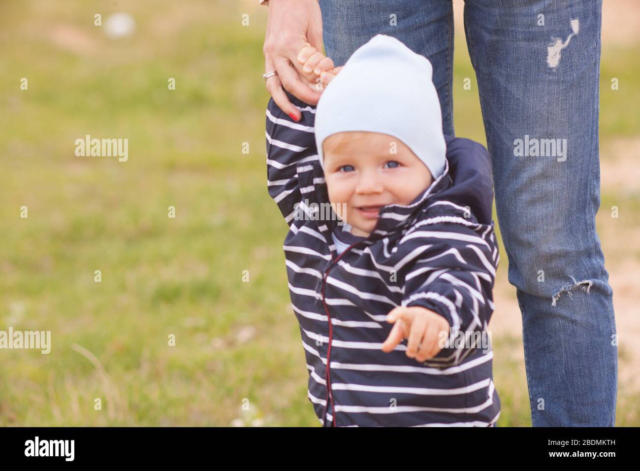 Une mère avec de longs cheveux maintient doucement son petit fils dans ses bras. Photo dans le parc avec lumière naturelle Banque D'Images