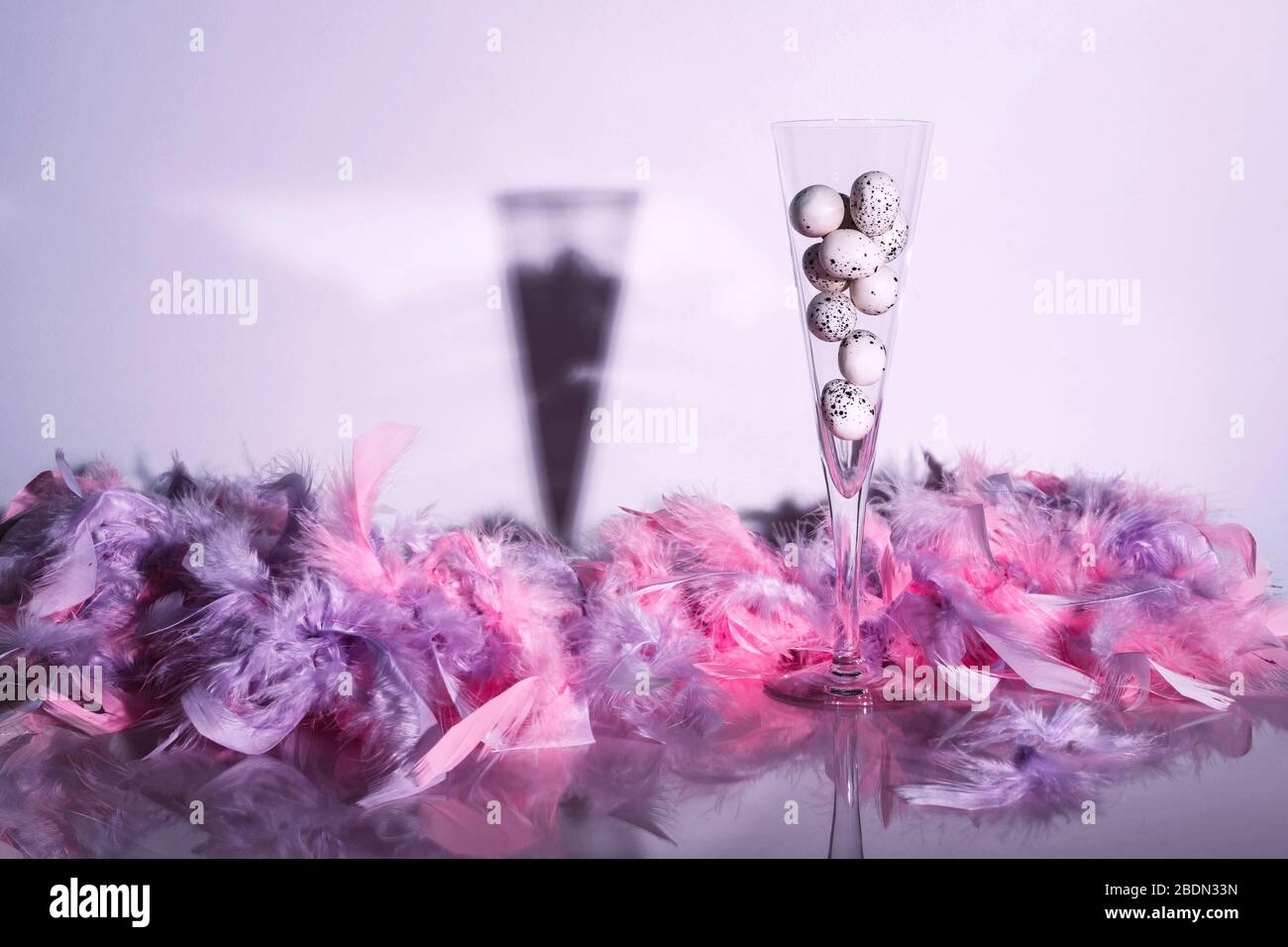 Œufs Quail dans flûte de champagne avec plumes sur fond brillant. Créativité toujours la vie. Concept de Pâques. Banque D'Images