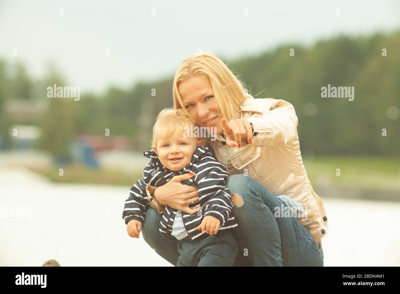 Mère seule transportant et ensergeant un enfant à l'extérieur près du lac avec fond jaune et blanc naturel Banque D'Images