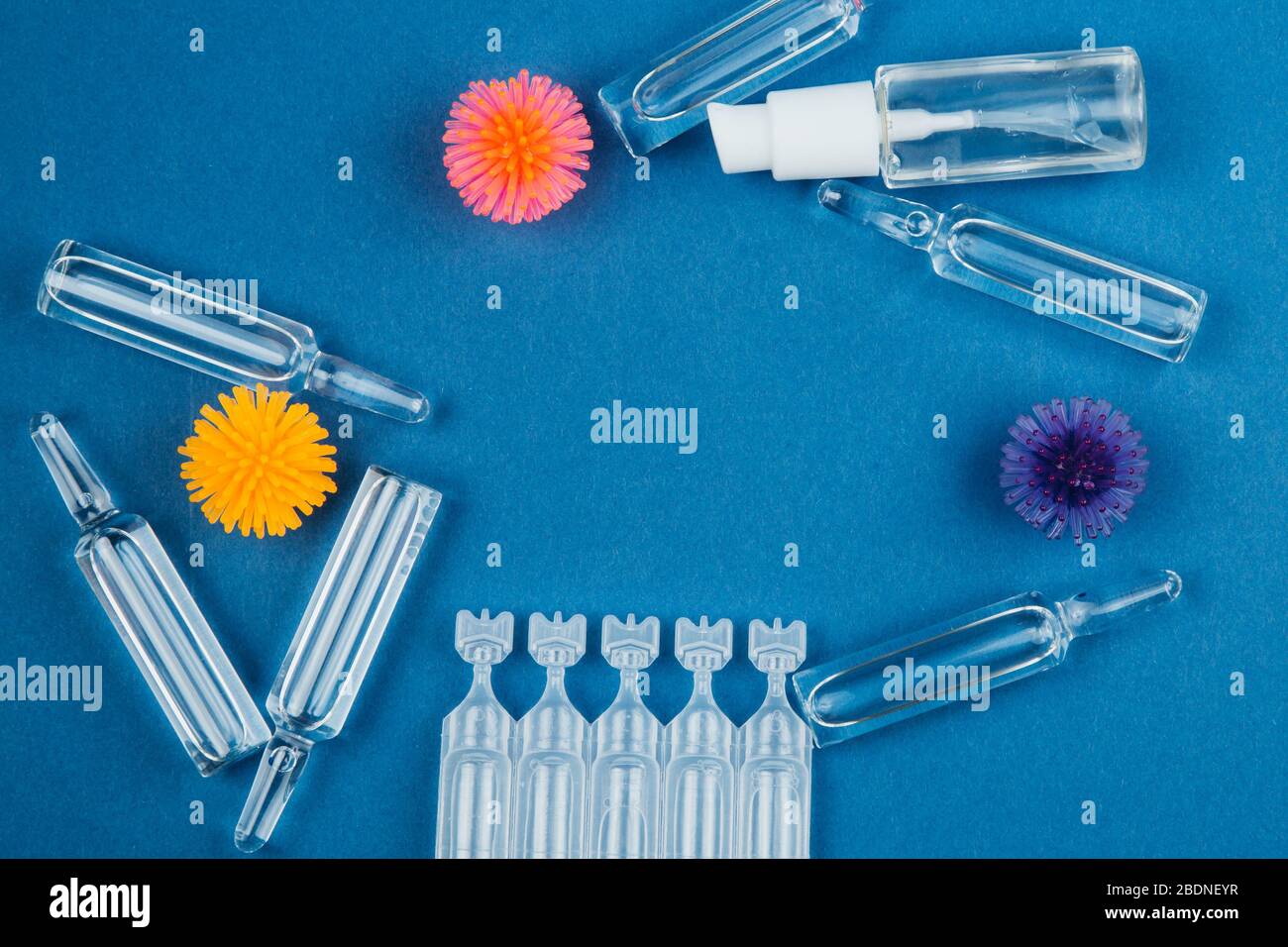 Modèle abstrait de coronavirus, ampoule avec médicament et flacon avec gel antibactérien pour les mains sur fond bleu. Banque D'Images