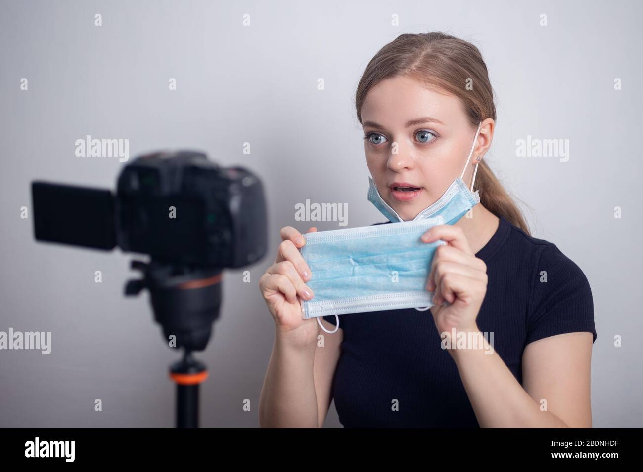 Jeune fille caucasienne souriante portant un masque, faisant un blog vidéo (vlog) avec caméra à la maison Banque D'Images