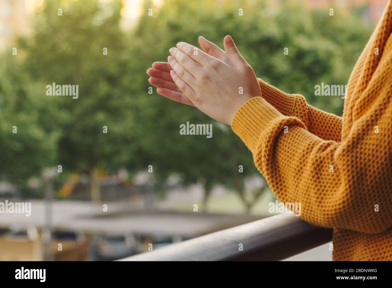 Stock photo des mains d'une jeune femme clapping du balcon pour soutenir l'équipe médicale Banque D'Images