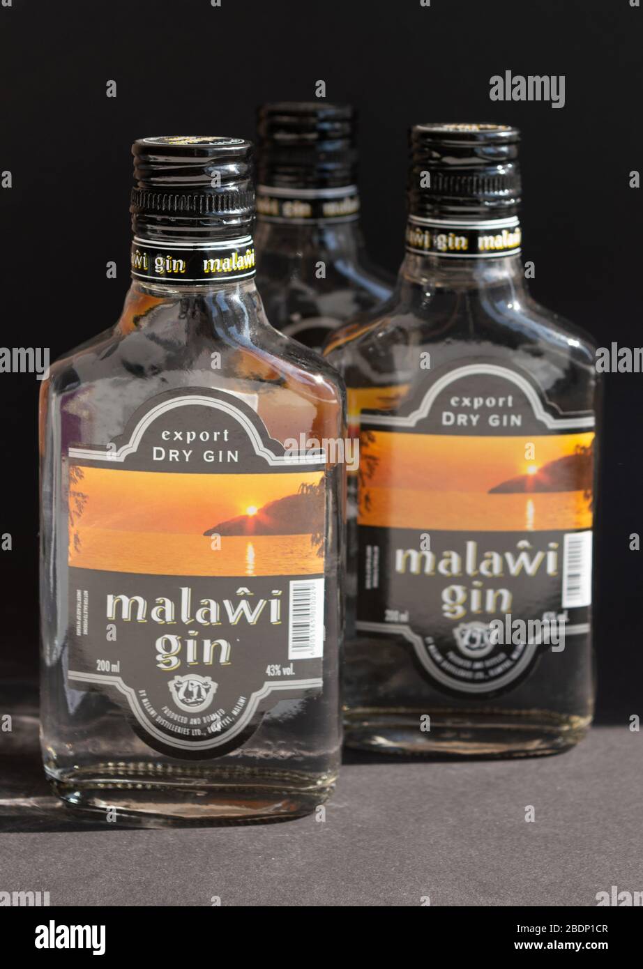 KIEV, UKRAINE - 03 AVRIL 2020: Photo verticale de trois bouteilles de verre de 200 ml de gin Malawi restant l'une après l'autre sur un fond sombre. Un national Banque D'Images