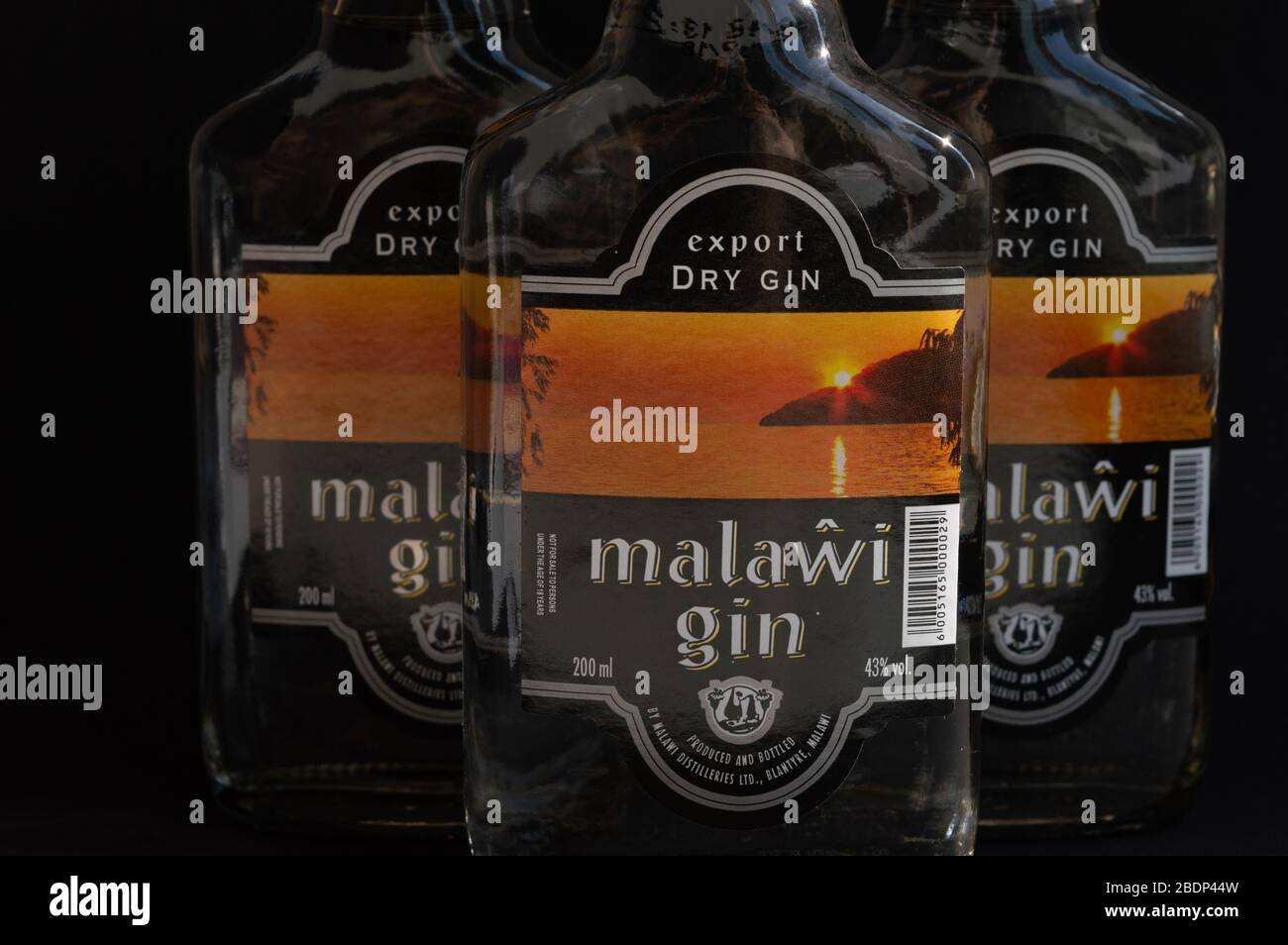 KIEV, UKRAINE - 03 AVRIL 2020: Gros plan de trois bouteilles de verre de 200 ml de gin Malawi en ligne sur un fond sombre. Un ressortissant malawian africain Banque D'Images