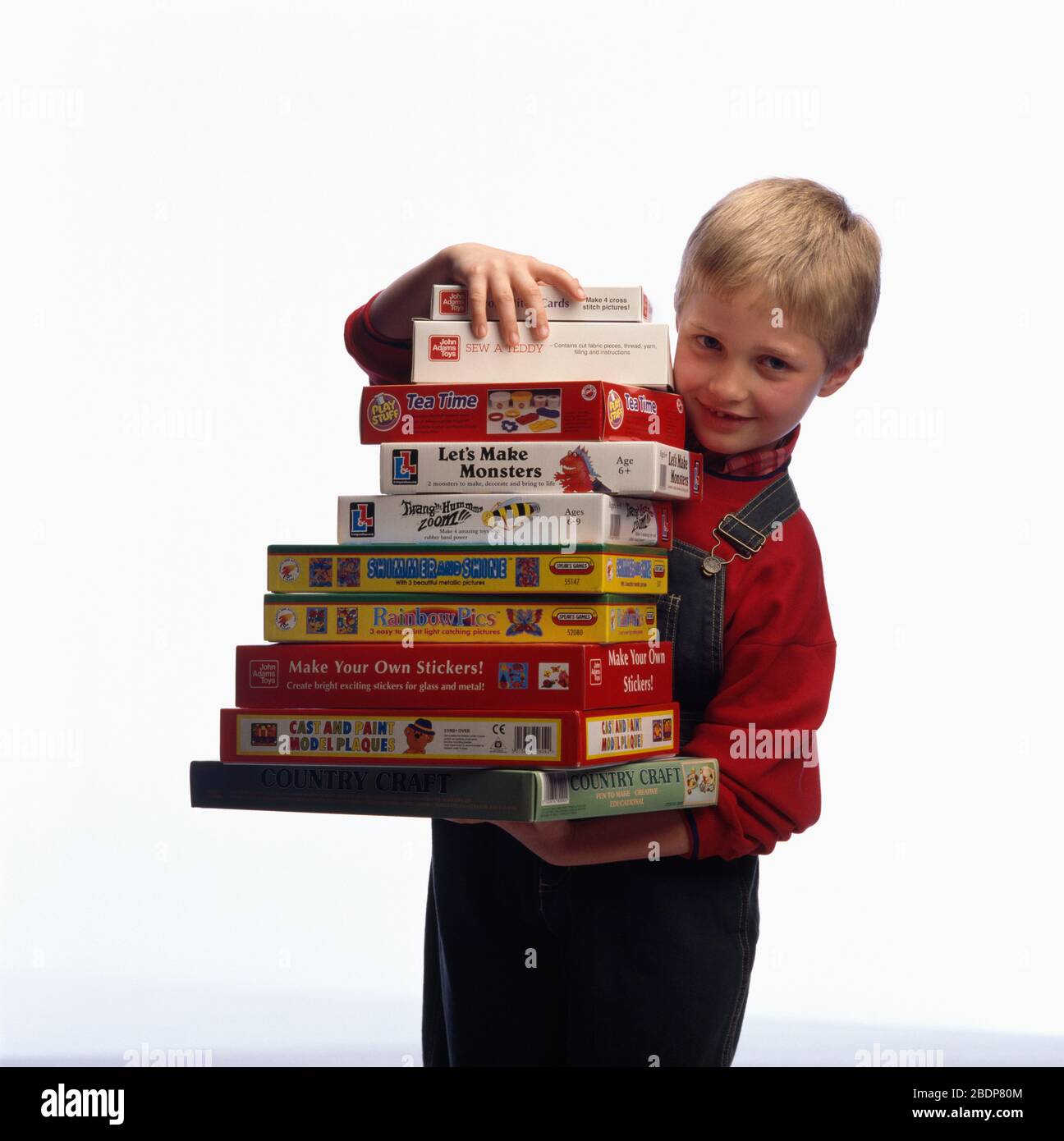 Garçon portant une grande pile de jeux de société POUR USAGE