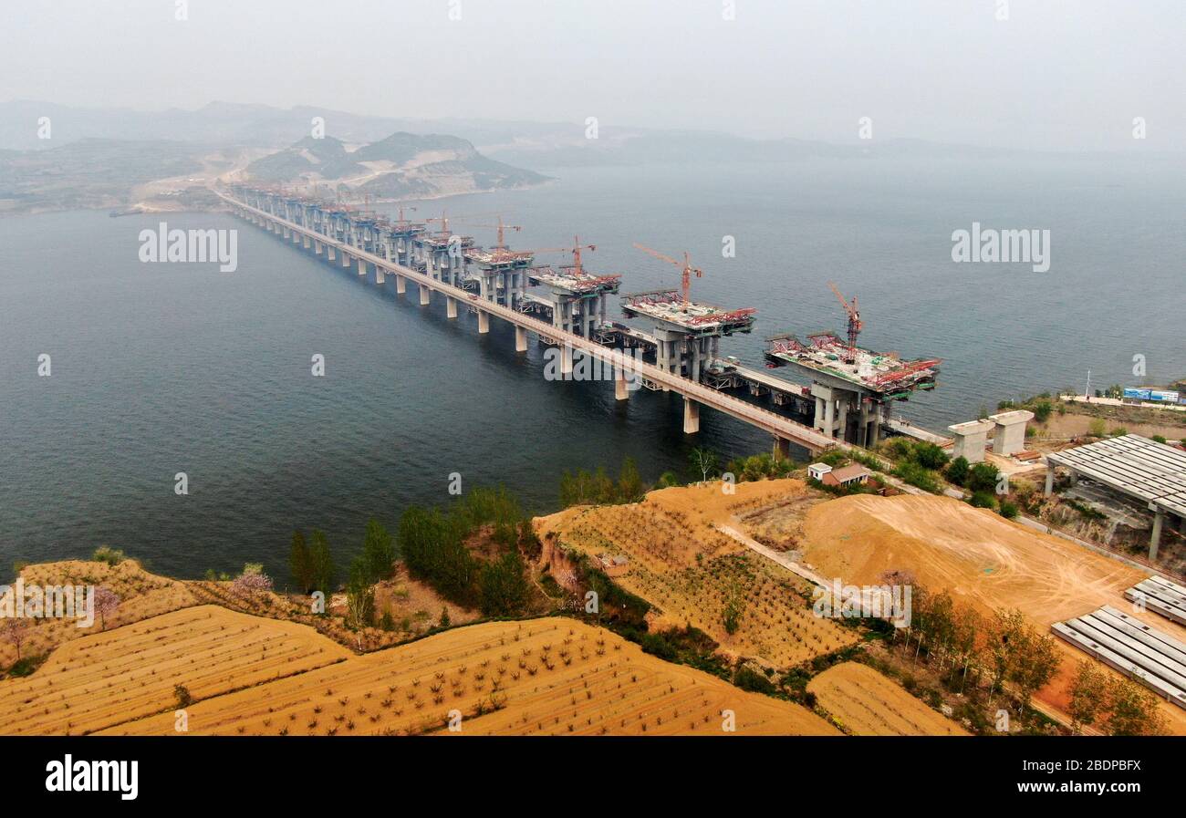 Zhengzhou. 9 avril 2020. La photo aérienne prise le 9 avril 2020 montre le chantier d'un pont de l'autoroute Mianchi-Yuanqu au-dessus de la rivière jaune, province du Henan au centre de la Chine. Le pont est une importante voie express interprovinciale reliant les provinces de Shanxi et de Henan, avec une longueur design de 1 757 mètres et une largeur de 33 mètres. Le projet devrait être achevé et ouvert au trafic d'ici la fin de 2020. Crédit: Zhu Xiang/Xinhua/Alay Live News Banque D'Images