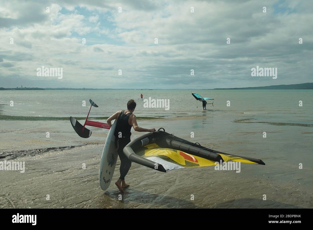 Deux hommes préparent leur équipement pour faire du carrelage dans les ailes à l'aide d'ailes gonflables et de planches de surf hydrofoil à Auckland Harbour. Banque D'Images