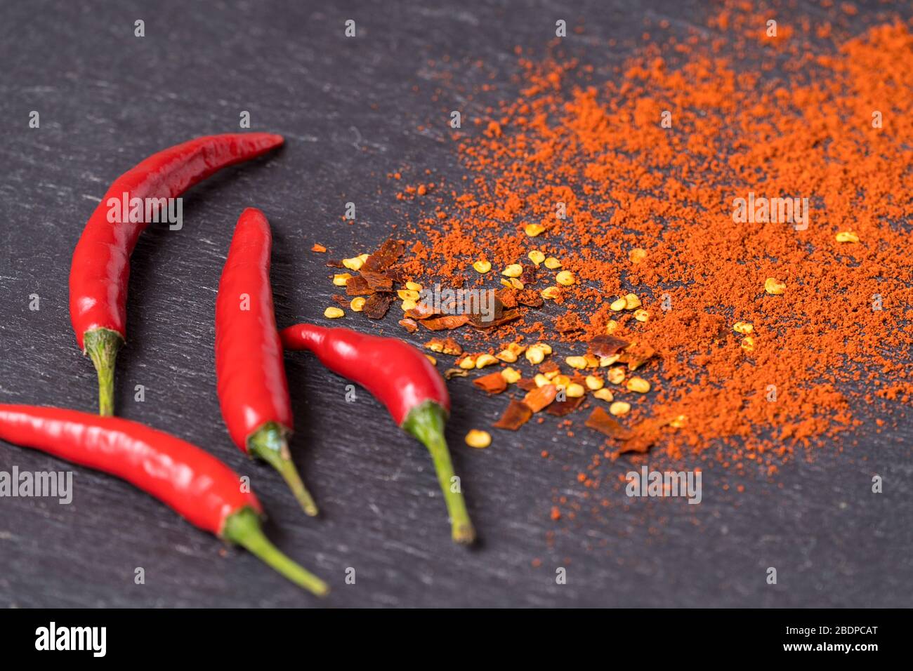 Plat posez des piments rouges chauds, des flocons de poivre rouge et de la  poudre de piment sur fond noir Photo Stock - Alamy