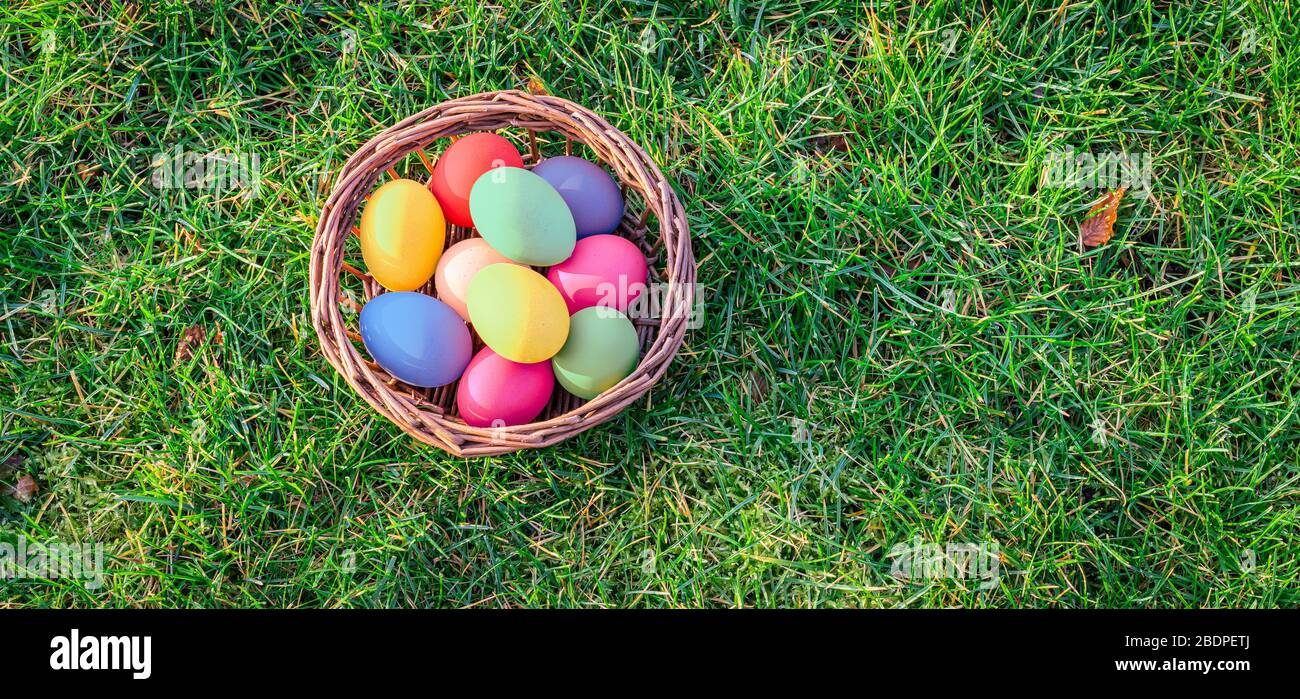 Vue sur le dessus des œufs de pâques colorés dans le panier sur l'herbe. Banque D'Images