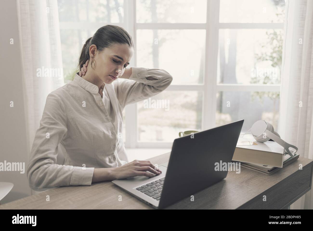 Yougn femme travaillant avec son ordinateur portable à la maison, elle a des douleurs au cou Banque D'Images