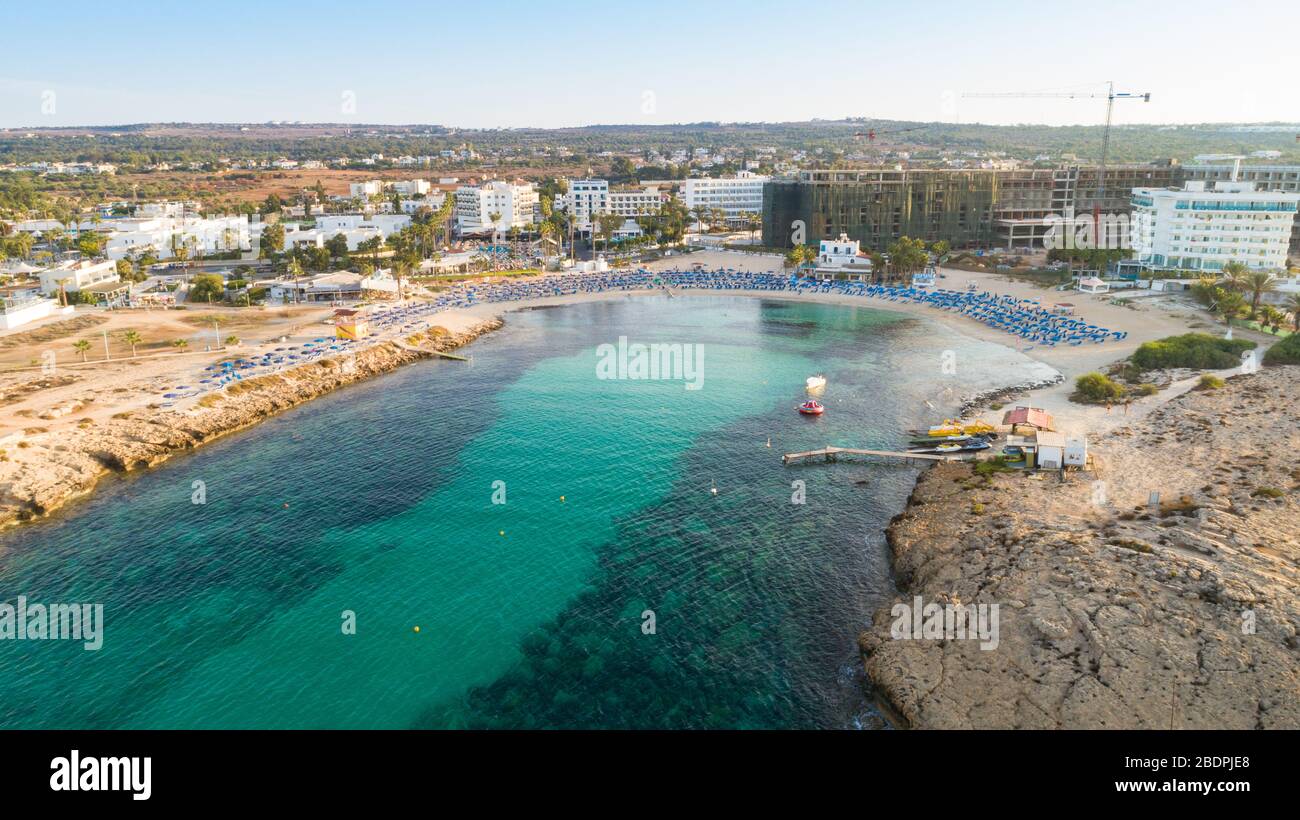 Vue panoramique sur la plage de Vathia Gonia, Ayia Napa, Famagusta, Chypre. L'attraction touristique historique baie rocheuse au lever du soleil avec sable doré, soleil Banque D'Images