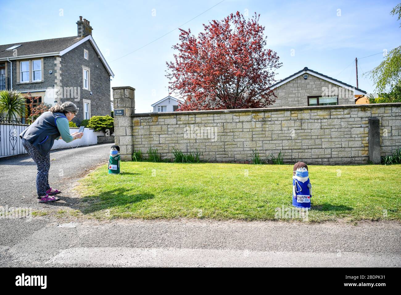 Une femme prend une photo de deux tricots NHS médecin est installé sur un bolard à l'extérieur d'une maison à Oldland Common, South Gloucestershire, comme le Royaume-Uni continue de maintenir le verrouillage pour aider à freiner la propagation du coronavirus. Banque D'Images