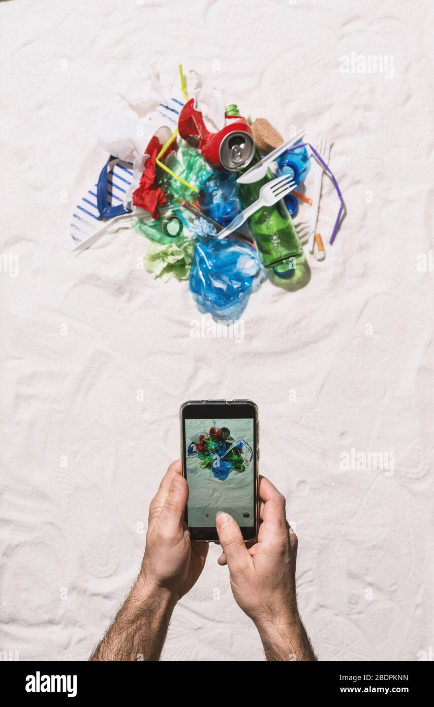 Homme prenant une photo de la pollution des déchets sur la plage et la partager en ligne à l'aide de son smartphone, protection de l'environnement et pollution plastique conceps Banque D'Images