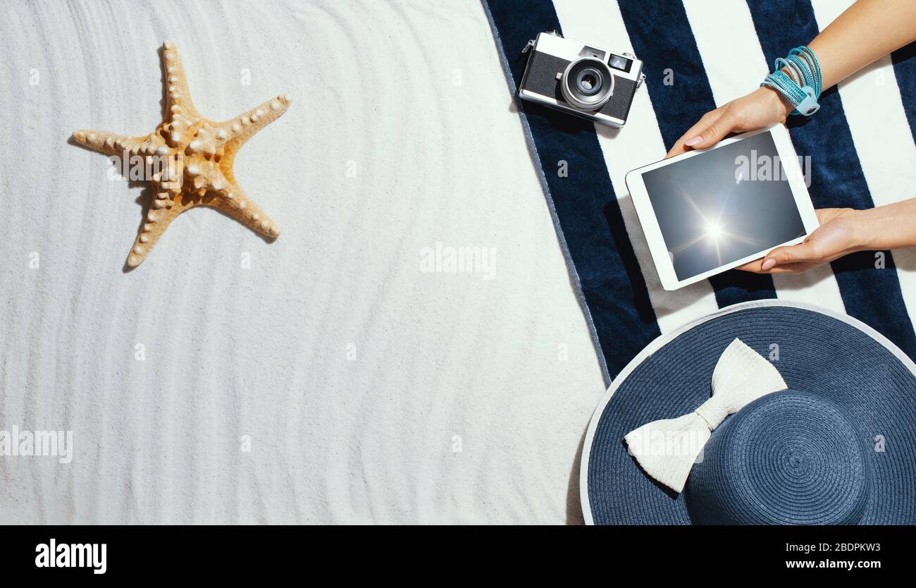 Femme se reposant sur la plage et se connectant en ligne avec une tablette, le bord de mer et le concept de vacances, copyspace vierge Banque D'Images