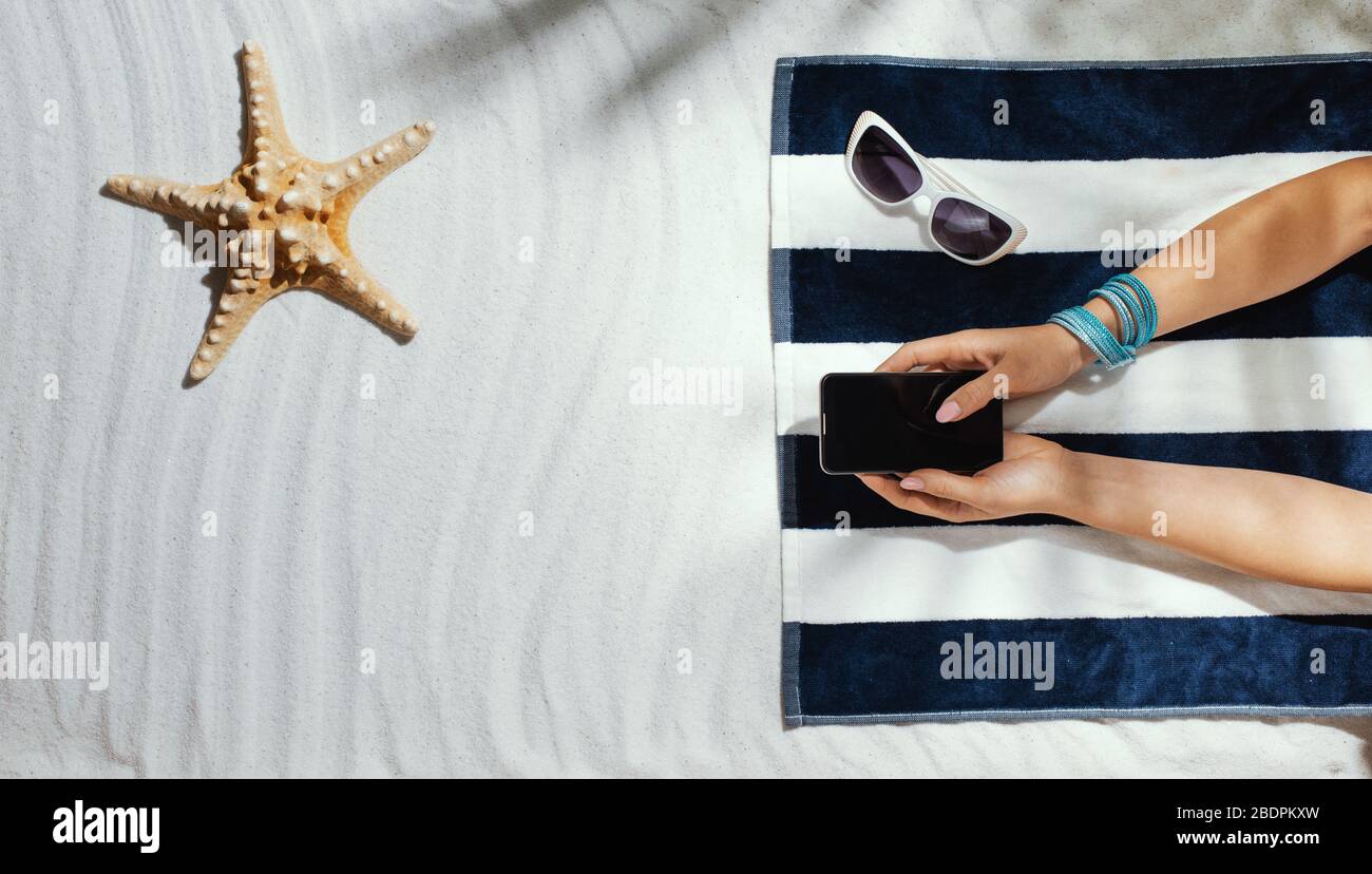 Femme allongé sur la plage et se connectant à l'aide de son smartphone, vacances d'été et concept de connexion Banque D'Images