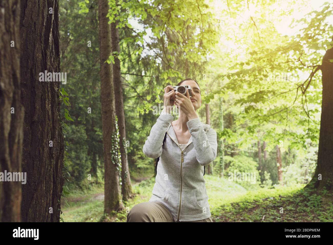 Jeune femme marchant dans la nature et prenant des photos à l'extérieur avec son appareil photo numérique, son hobby et son concept d'environnement Banque D'Images