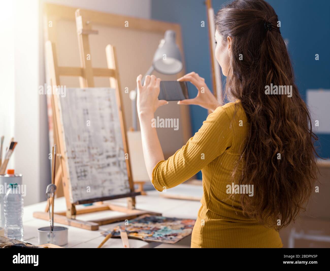 Belle fille prenant une photo de sa peinture à l'aide de son smartphone, technologie et concept d'art Banque D'Images