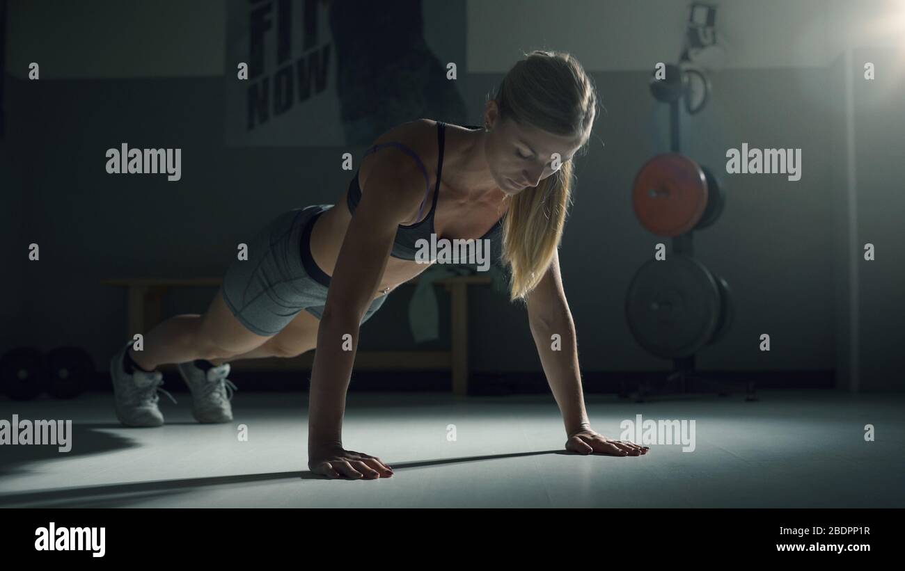 Femme musculaire athlétique faisant des poules dans la salle de gym, le concept de forme physique et de sport Banque D'Images