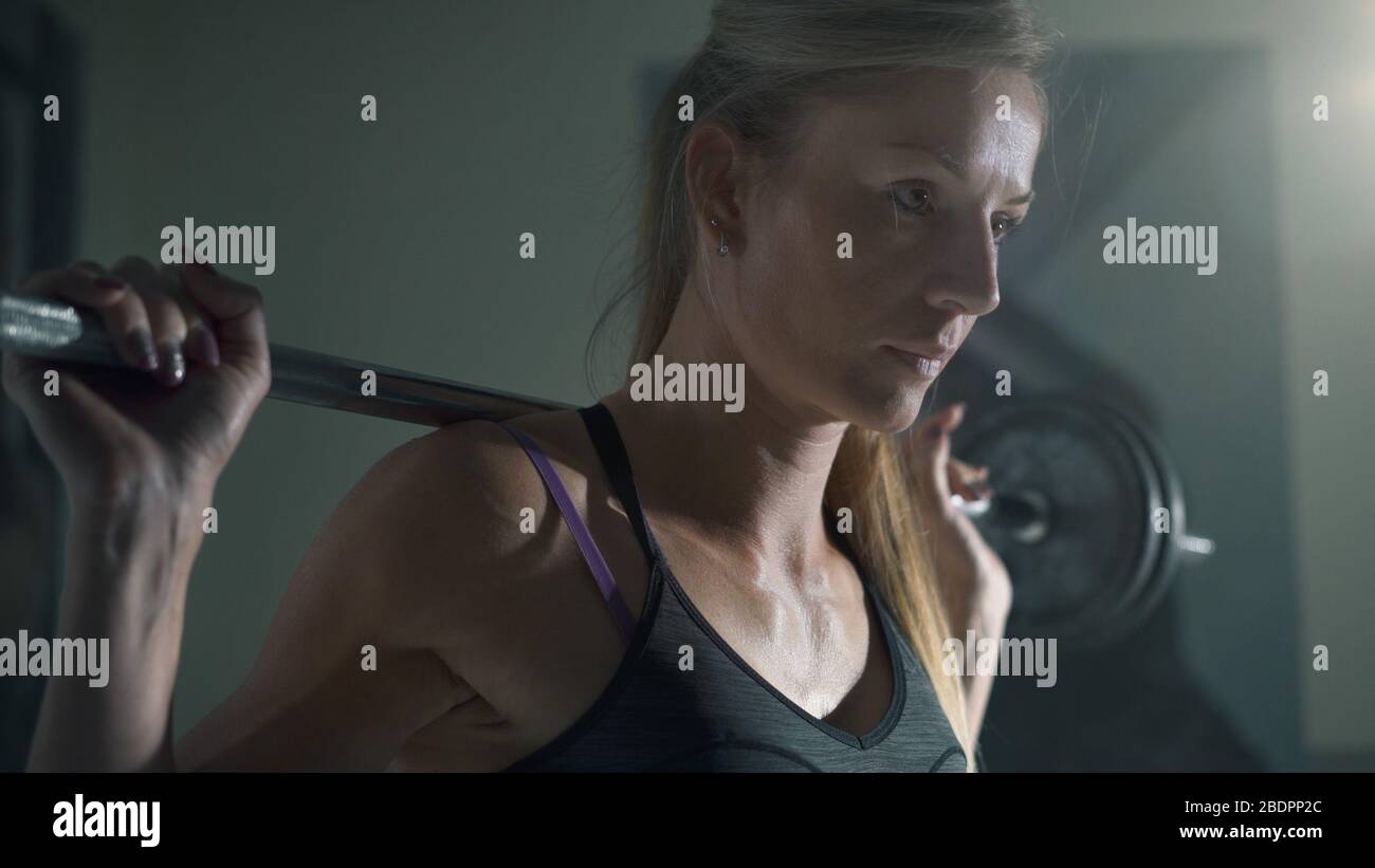 Femme de culturisme athlétique travaillant à la salle de gym, elle fait haltérophilie avec une barbelette Banque D'Images