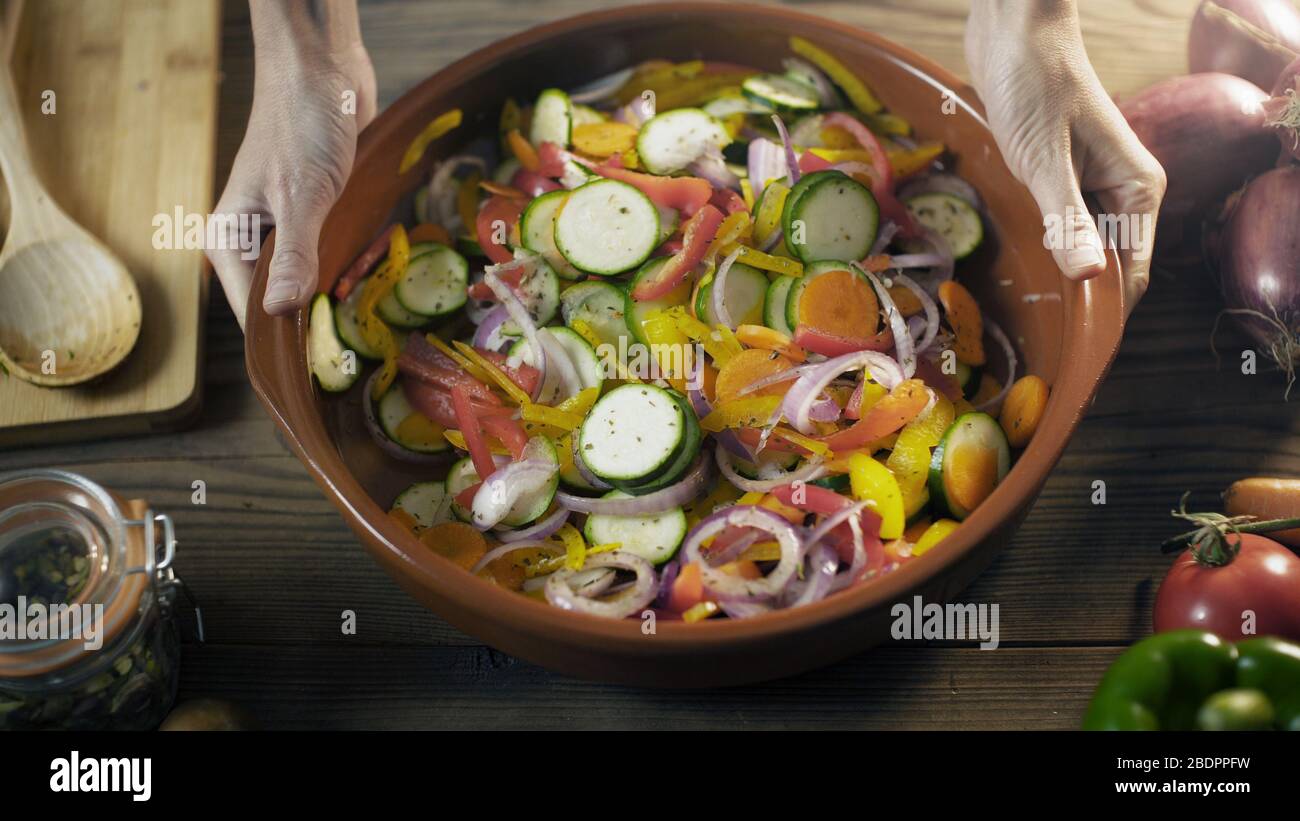 Préparation de repas végétalien dans la cuisine: Légumes frais bio mélangés dans une casserole d'argile, concept de nourriture saine Banque D'Images