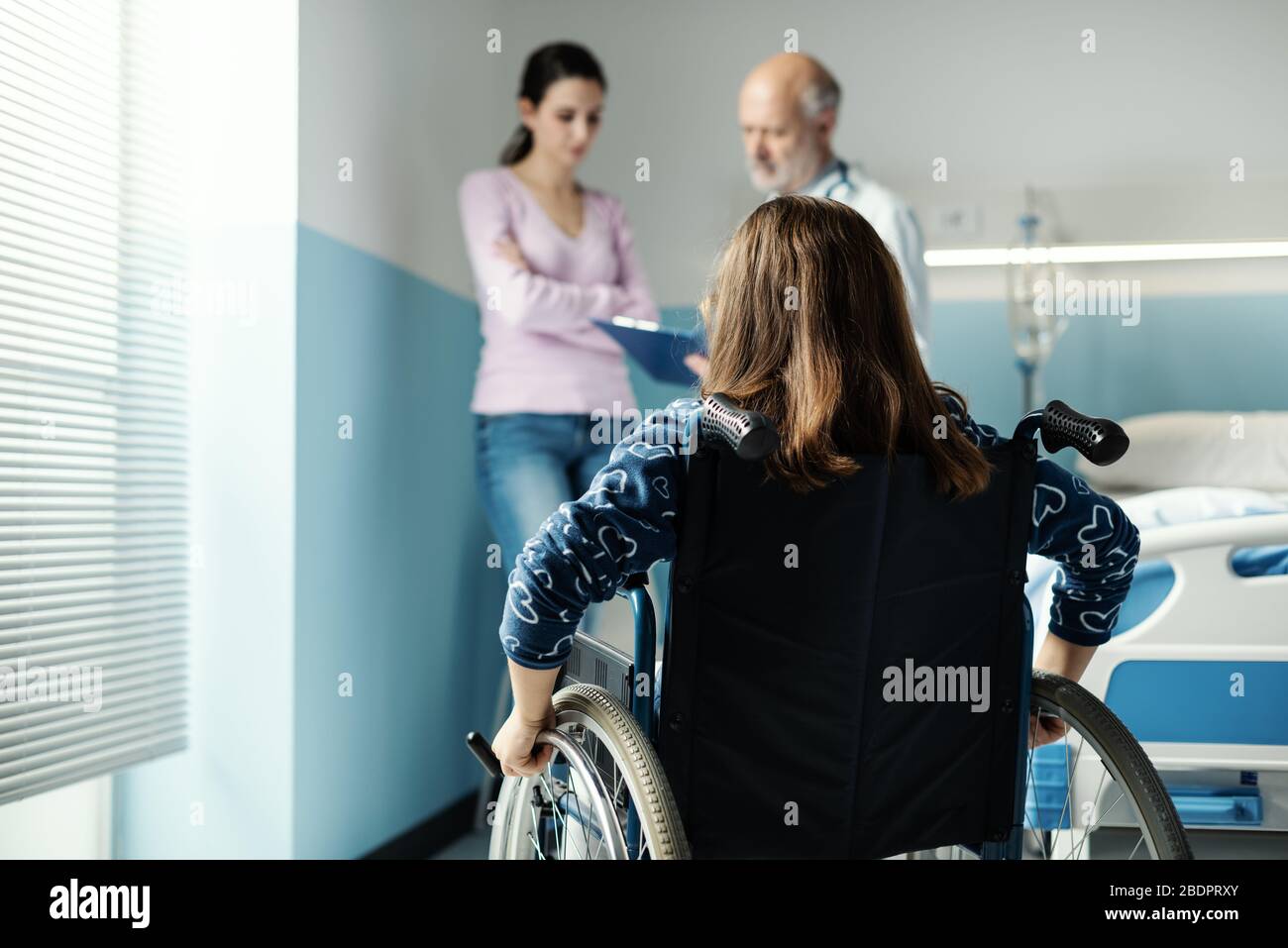 Fille en fauteuil roulant à l'hôpital, sa mère et le médecin discutent de sa santé Banque D'Images