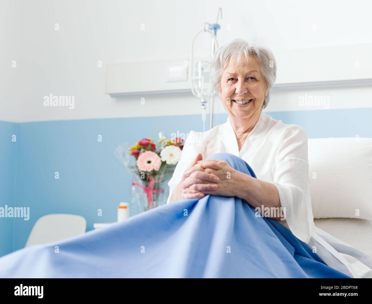 Femme âgée souriante se posant dans un lit d'hôpital et regardant la caméra, les soins de santé et le concept de soins de haute direction Banque D'Images