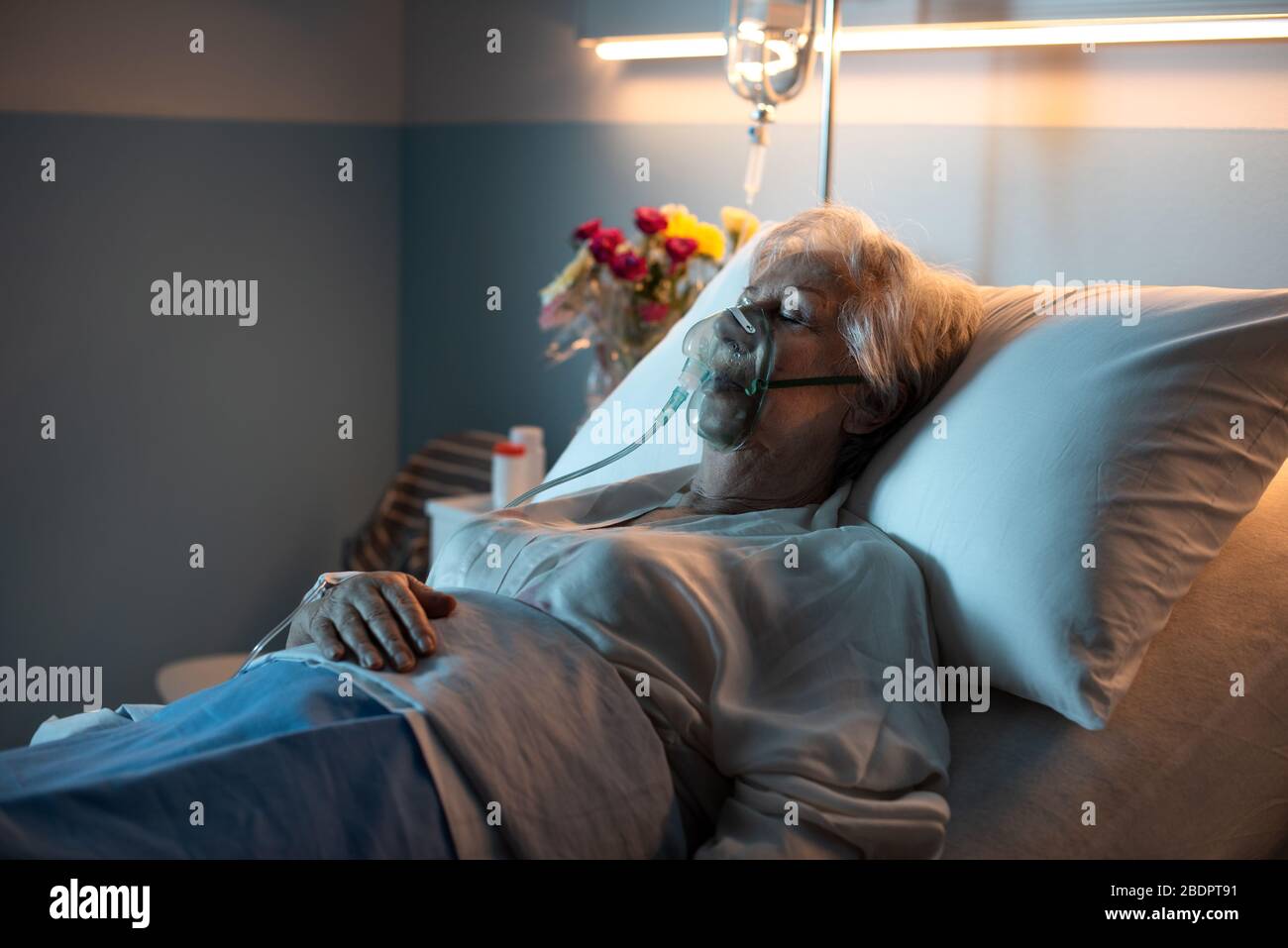 Femme âgée posée au lit à l'hôpital, elle porte un masque à oxygène et dort Banque D'Images