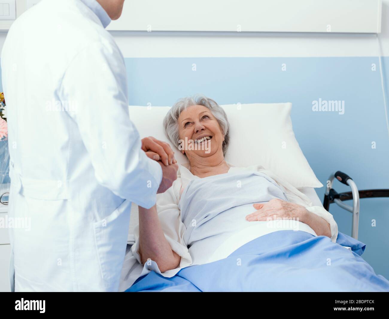 Médecin visitant un patient hospitalisé de haut niveau à l'hôpital, il tient sa main, la souriant et la réconfortant, concept de soins de haut niveau Banque D'Images