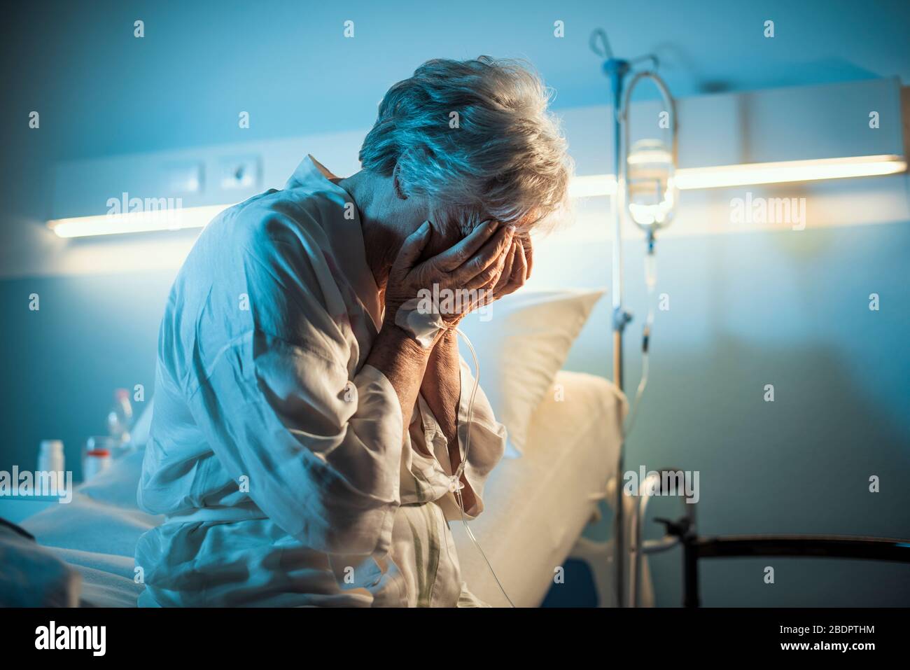 Patient solitaire assis sur le lit de l'hôpital et pleurant avec la tête dans les mains Banque D'Images