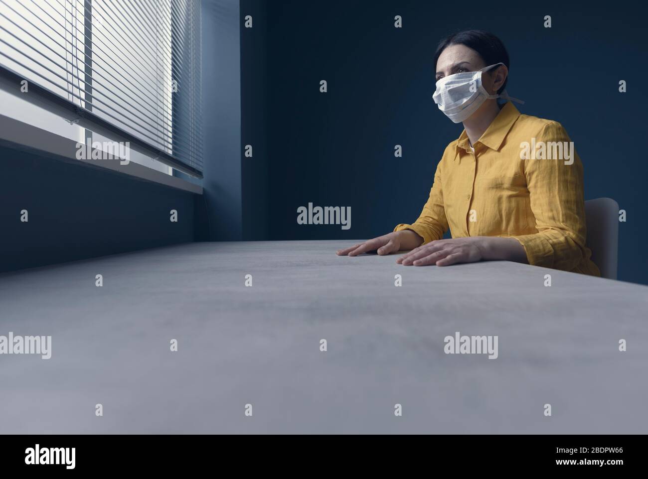 Femme solitaire en quarantaine avec covid-19 portant un masque de visage et assis à la maison seule devant une fenêtre, concept d'urgence d'épidémie de virus Banque D'Images