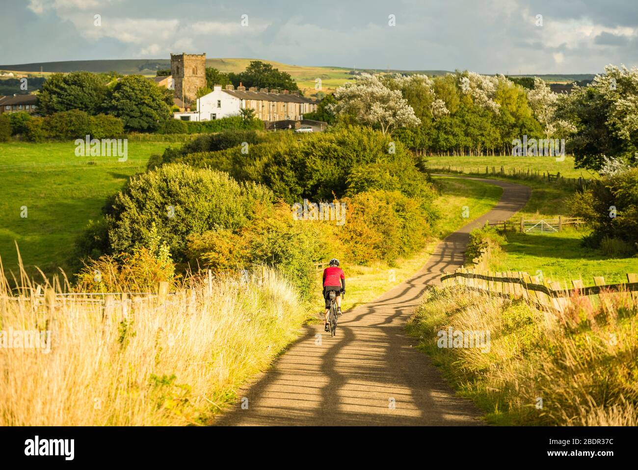 Femme vélo sur le chemin libre de voiture sous l'église, Lancashire, une partie de la Greenway de Hyndburn Banque D'Images