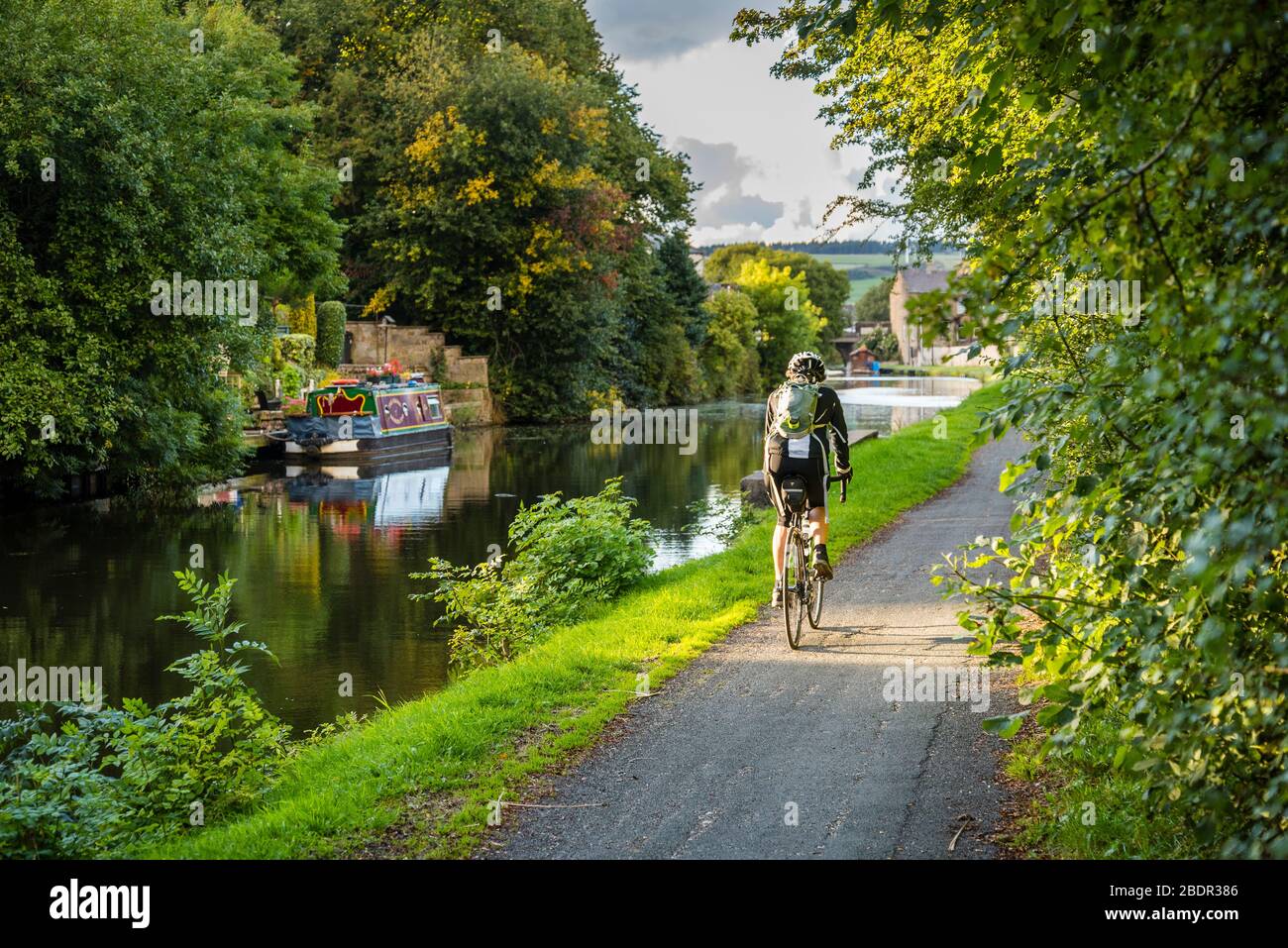 Femme vélo sur le chemin de remorquage du canal de Leeds et Liverpool à Rischton, Lancashire Banque D'Images