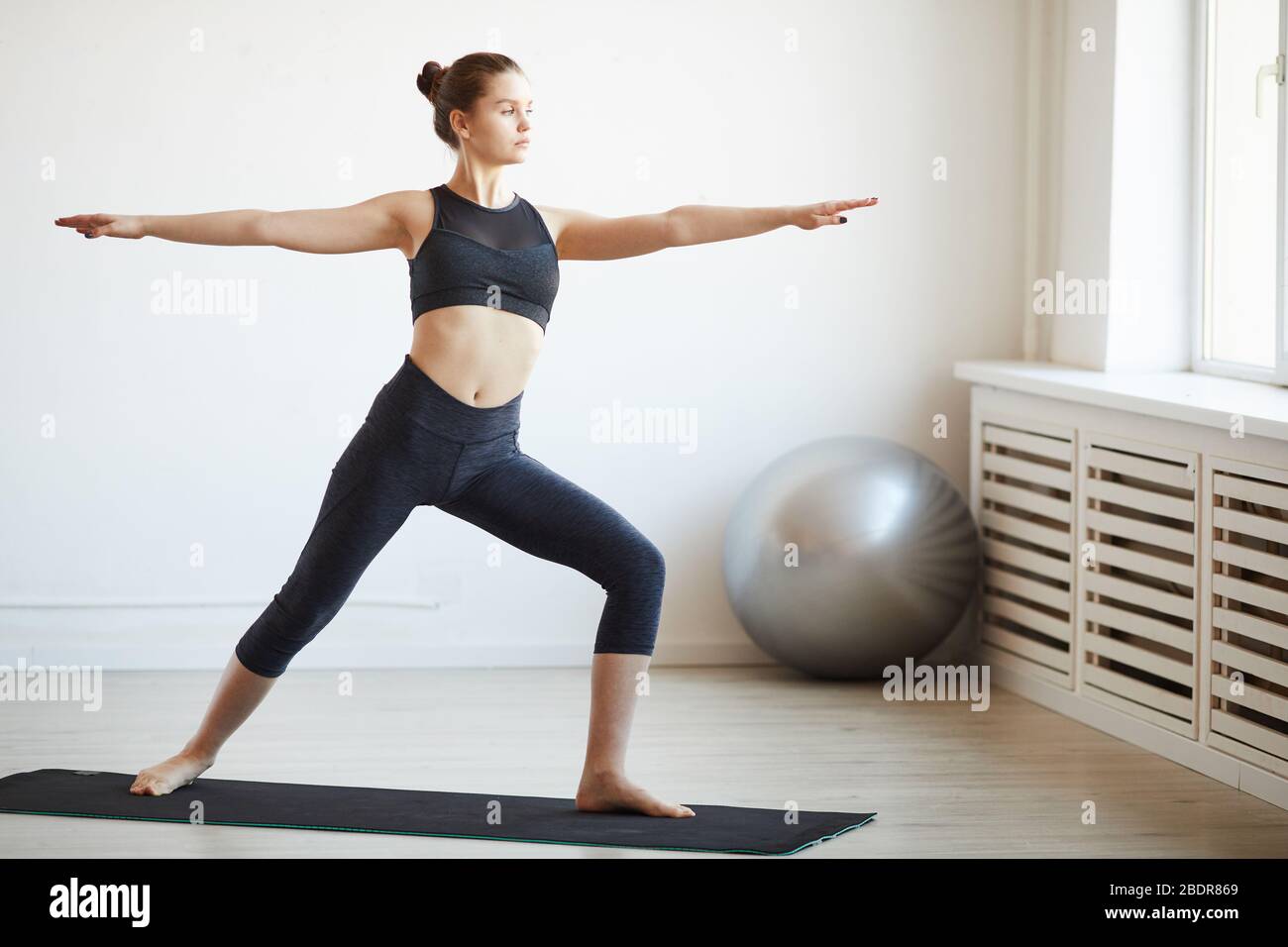 Jeune femme en bonne santé debout sur un tapis d'exercice et s'exerçant dans un club de santé Banque D'Images