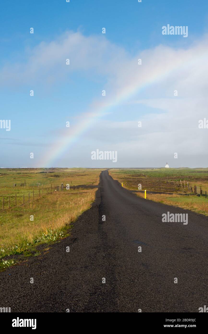 Un arc-en-ciel sur la route du tarmac jusqu'à Strandarkirkja dans le sud de l'Islande Banque D'Images