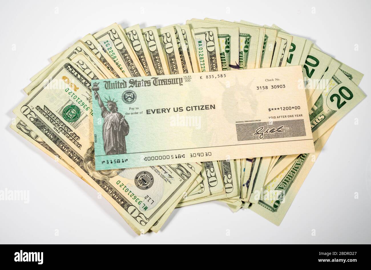 Pile de billets de 20 dollars avec un chèque illustratif de Trésor américain pour illustrer le paiement de relance du coronavirus sur fond blanc Banque D'Images