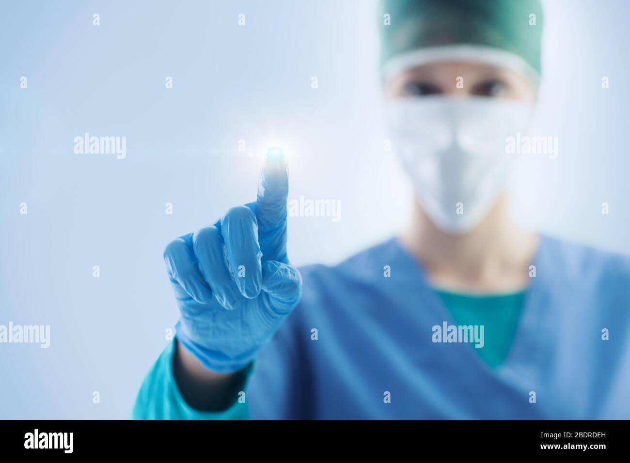 Chirurgien féminin utilisant une interface à écran tactile, elle pointe avec son doigt, la santé et le concept technologique Banque D'Images