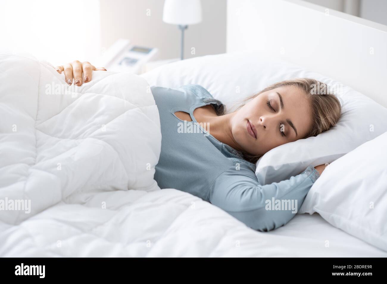 Belle jeune femme de dormir dans le lit, elle est relaxant et de rêver avec les yeux fermés, elle est pour elle-même avec la couette moelleuse Banque D'Images