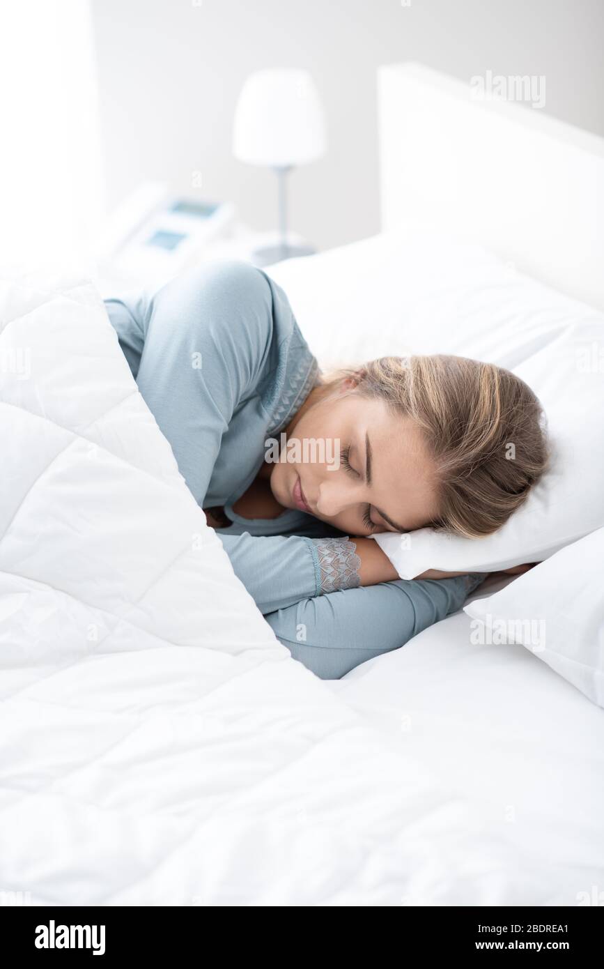 Jeune femme séduisante dormant dans la chambre, elle est posée sur le côté et se détendant avec les yeux fermés Banque D'Images