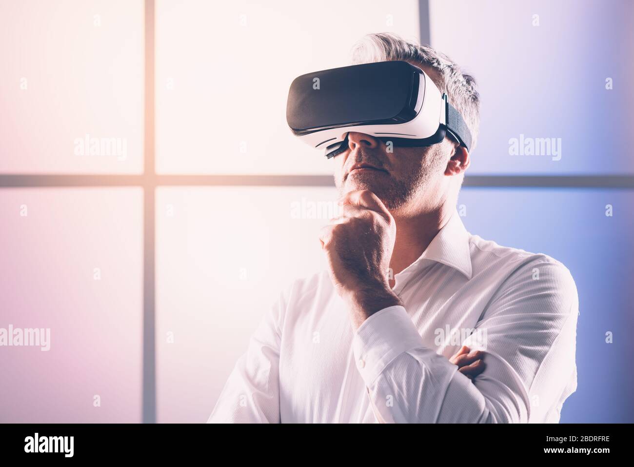 Homme d'âge mûr connaissant la réalité virtuelle, il porte un casque VR, une technologie et un concept d'innovation Banque D'Images