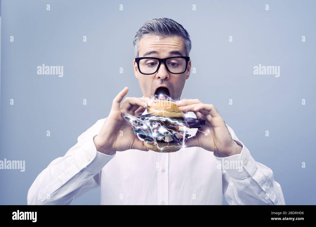 Un amateur de technologies INFORMATIQUES avide de de gourmands mangeant un sandwich rempli de matériel et de pièces d'ordinateur Banque D'Images