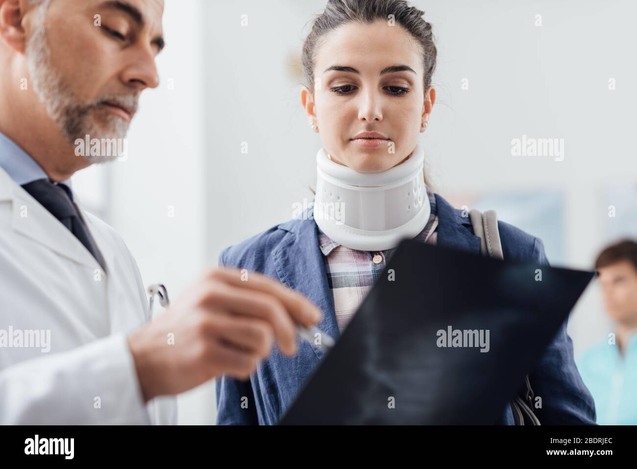 Médecin examinant la radiographie d'une jeune femme, elle porte un col cervical et a une grave lésion spinale Banque D'Images