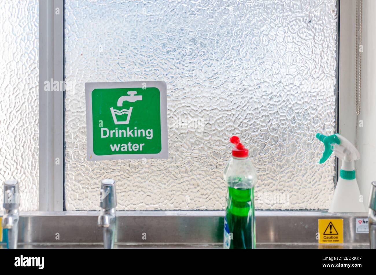 Panneau d'eau potable avec texte blanc et symbole robinet et symbole verre sur fond vert sur fenêtre de verre. Banque D'Images