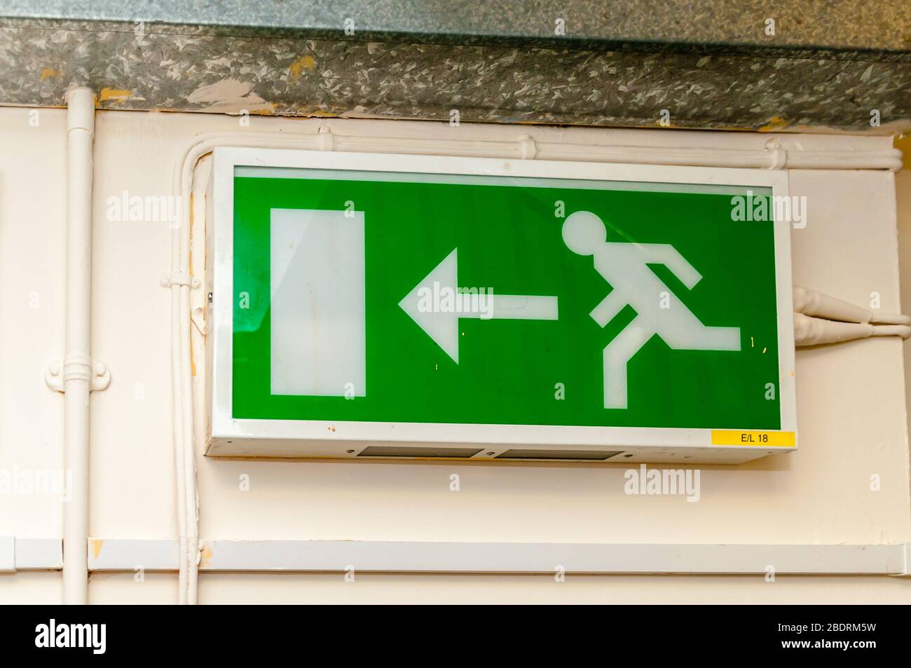 Une plaque de signalisation de sortie verte au néon avec un personnage désactivé, un personnage homme et une flèche vers la porte comme instructions pour les directions en cas d'urgence Banque D'Images