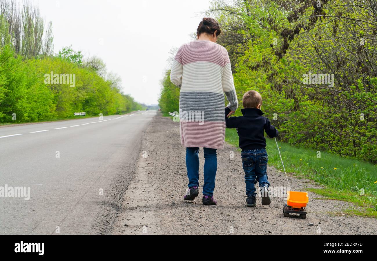 L'enfant avec sa mère marchant le long de la route. Banque D'Images