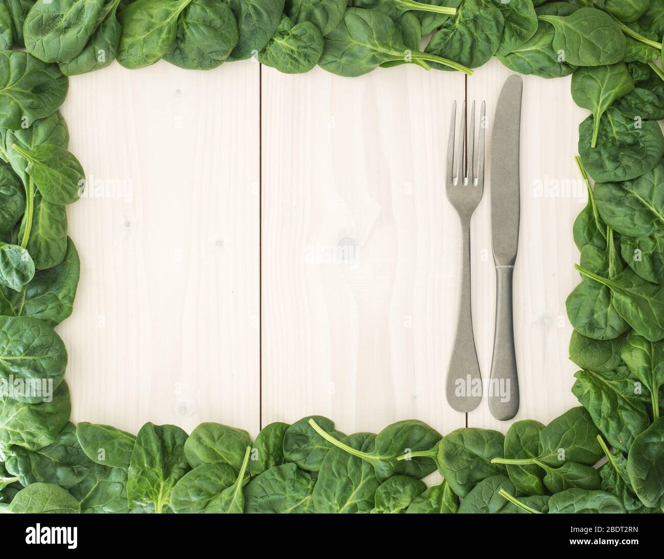 Cadre en feuilles d'épinards frais et couverts sur planche en bois. Vue sur le dessus Banque D'Images